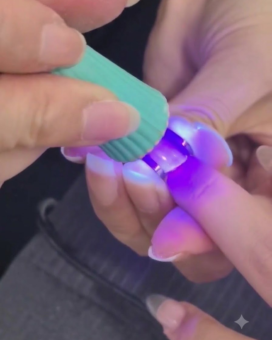 Una mini lampada UV o LED che polimerizza uno strato di gel per unghie strutturato su un dito.