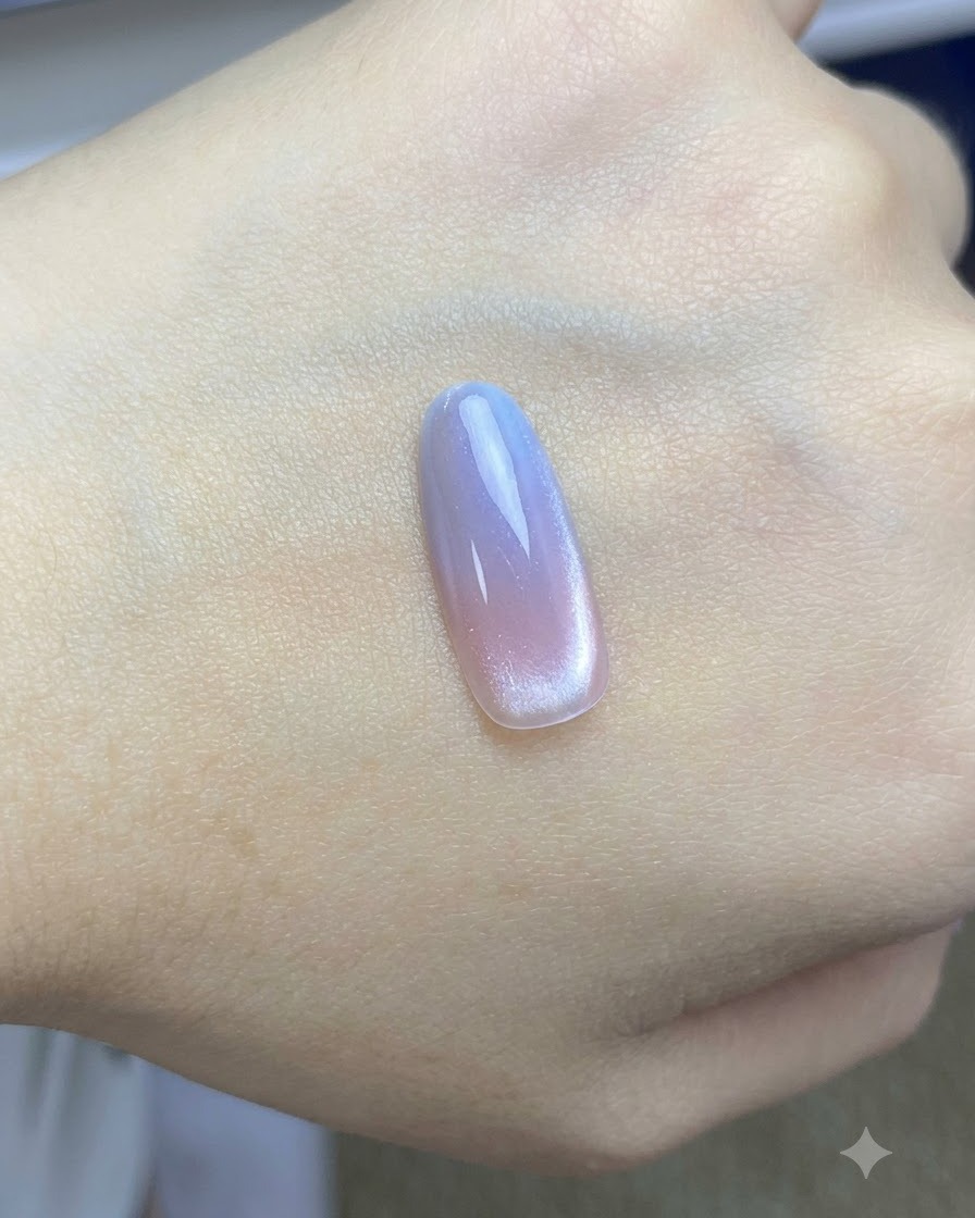 Un pennello che stende un top coat lucido finale sul design cat-eye rosa e blu completato.