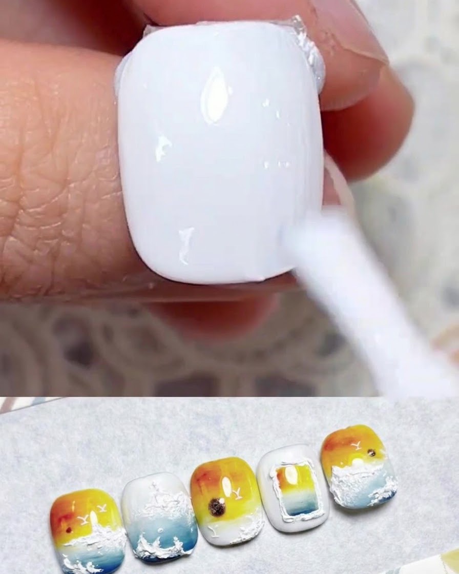 Un pennello per unghie che applica una mano uniforme di smalto semipermanente bianco latte su ununghia naturale.