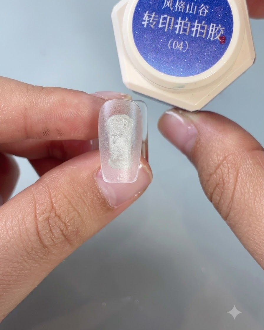 Un pennello applica il gel per stamping di trasferimento n. 4 al centro di una punta di unghia opaca per esercitazione.