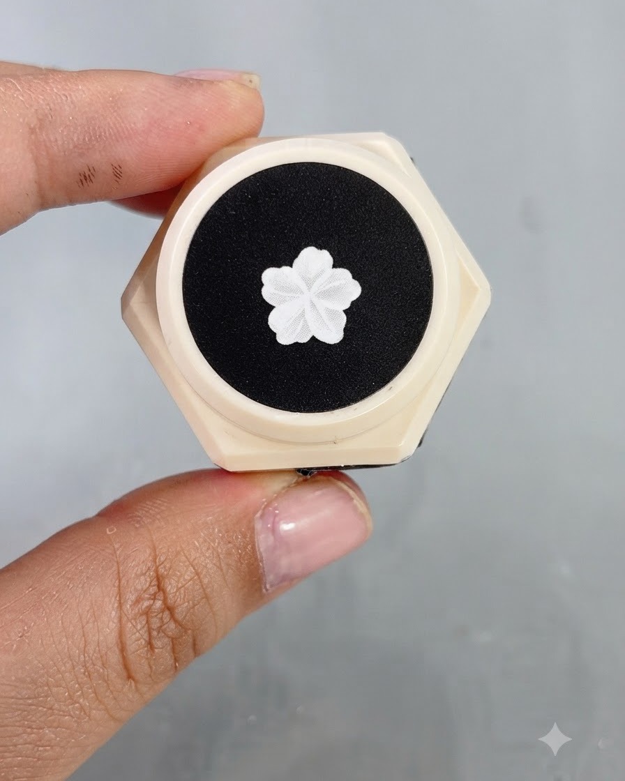 Primo piano di un pennello fine che crea contorni precisi di ali di farfalla bianche e piccoli accenti di stelle su ununghia decorata.