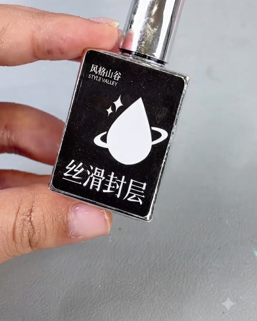 Una bottiglia nera con tappo argentato e unicona a goccia bianca etichettata con del testo, che rappresenta il gel top coat liscio.