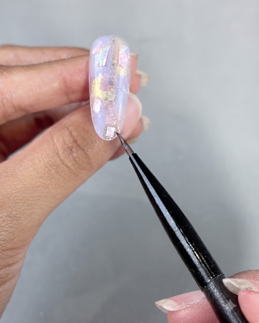 Una mano posta sotto una lampada per unghie UV LED per polimerizzare i pezzi di conchiglia applicati e il builder gel.