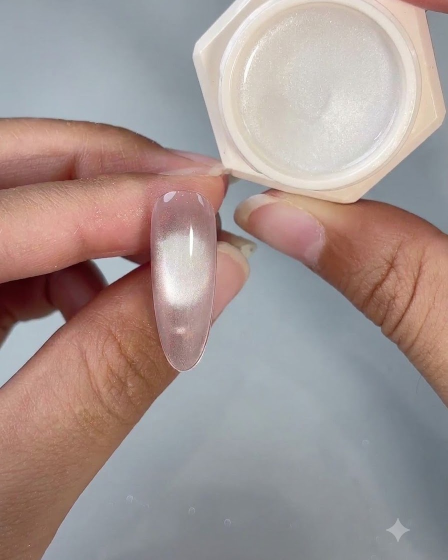Ununghia rifinita con gel cat eye mostrata accanto al vasetto di prodotto aperto sotto lilluminazione da studio.