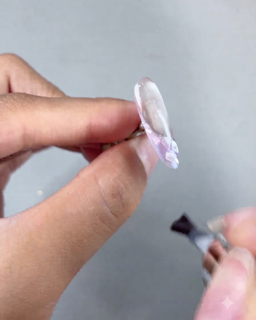 Un pennello che applica il soft builder gel su unestensione per unghie decorata prima della polimerizzazione.