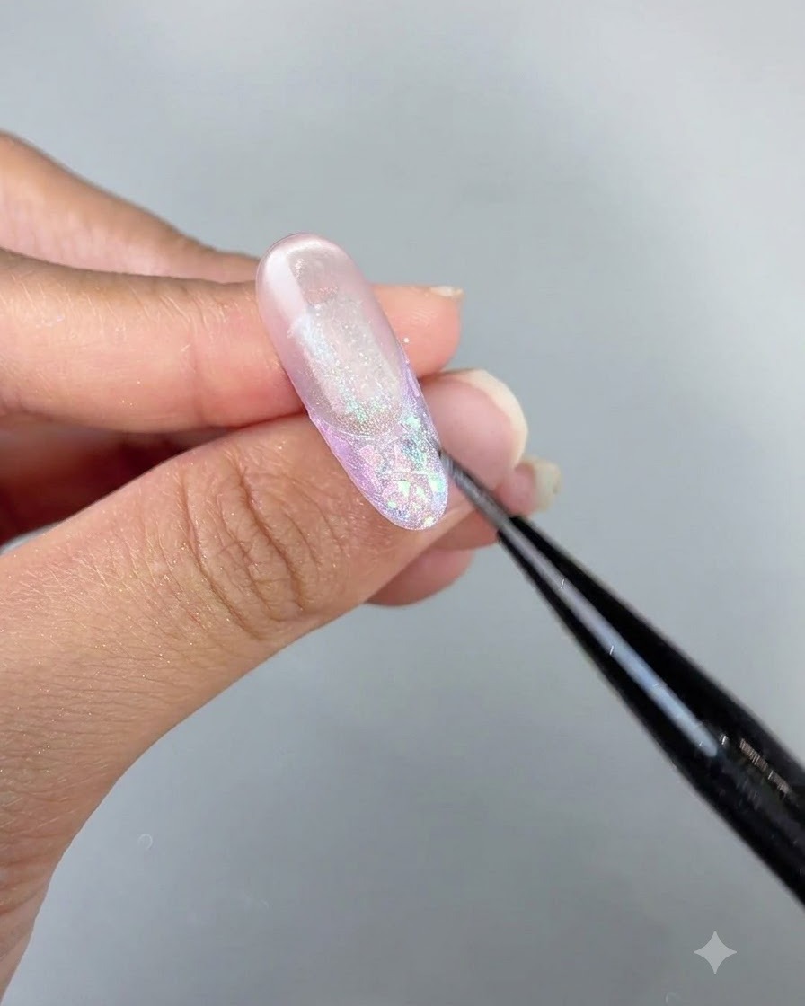 Un primo piano dettagliato di un pennello che perfeziona i dettagli del gel cat eye su un design di unghie lungo e lucido.