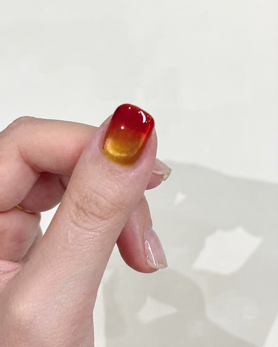 Una mano sollevata contro uno sfondo neutro, che mostra la texture liscia della sfumatura e la finitura lucida dellunghia.