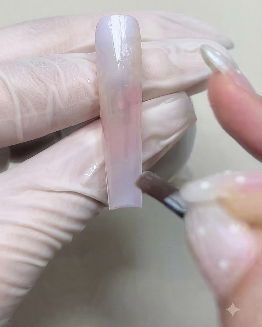 Un pennello che applica un secondo strato di gel colorato per approfondire la transizione sfumata sullunghia.