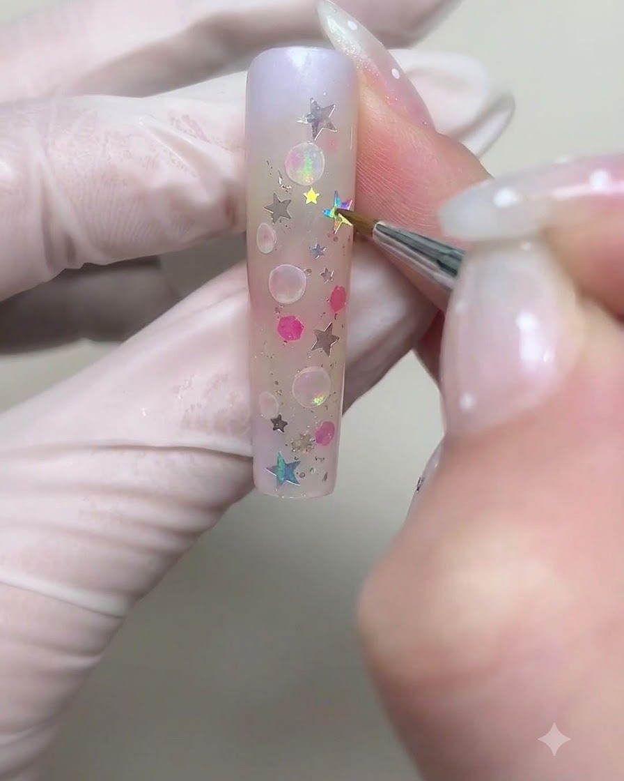 Un pennello sottile che disegna contorni circolari di bolle più grandi con gel cremoso bianco sullunghia.
