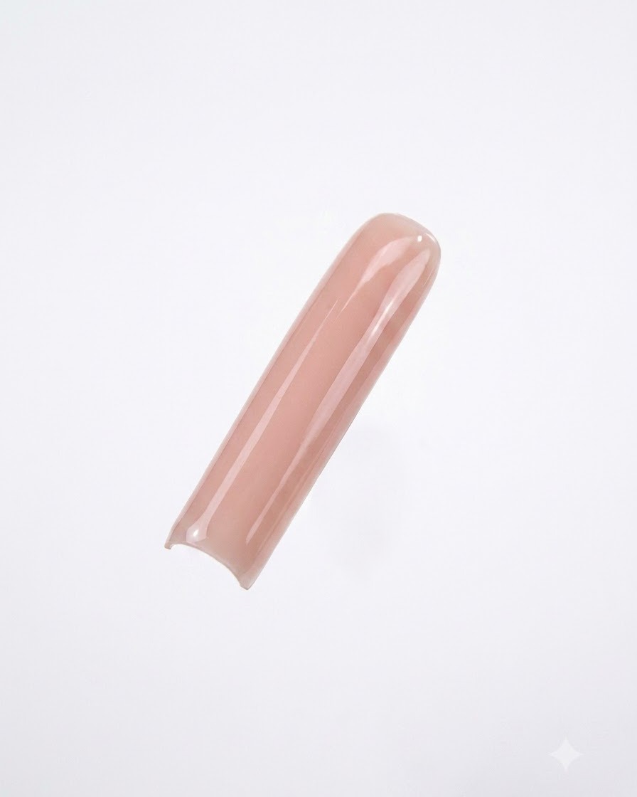 Una tip per unghie lunga e quadrata dipinta con uno smalto gel nude liscio e coprente su sfondo bianco pulito.