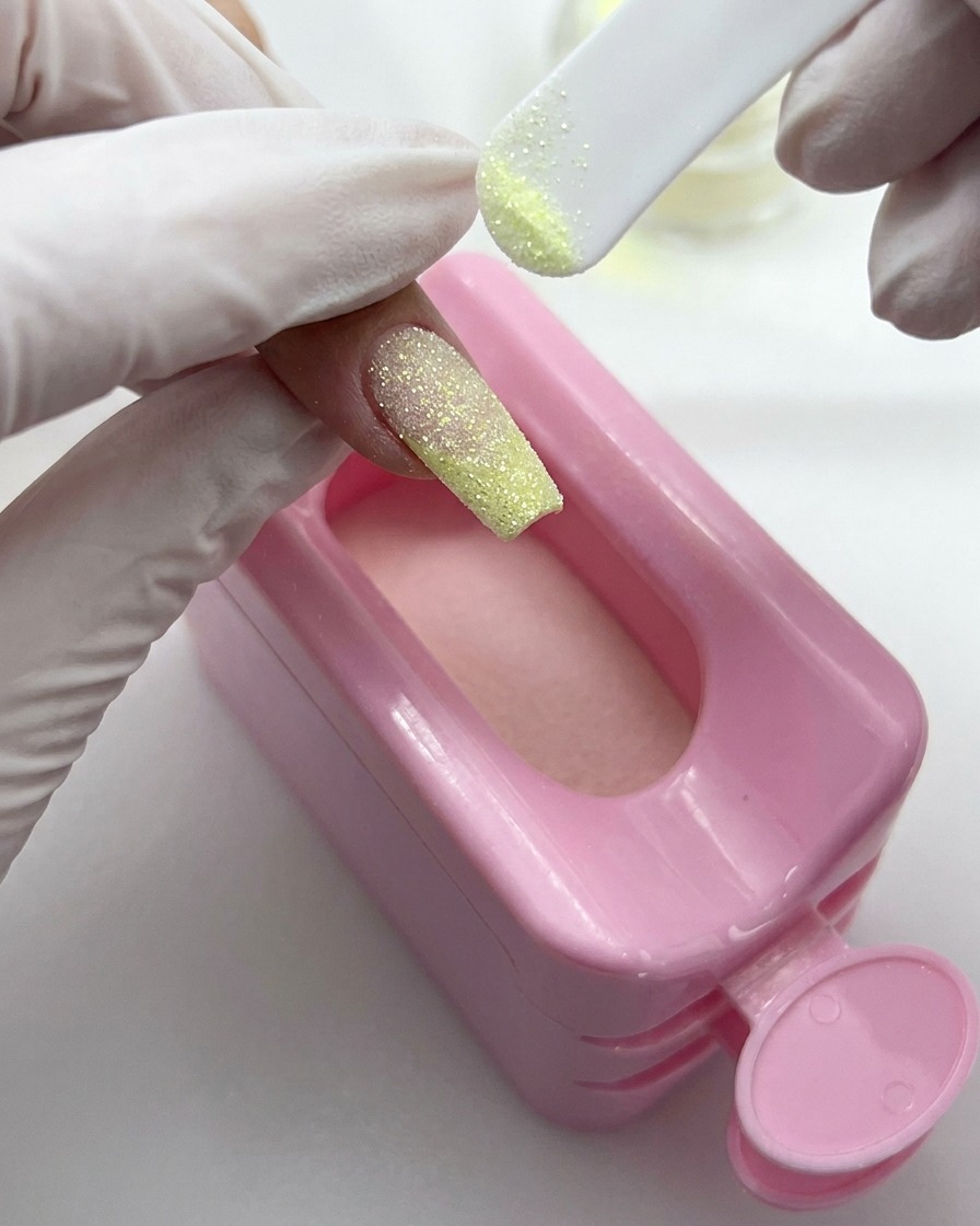 Un piccolo pennello da polvere che spazza via i glitter in eccesso dalla superficie di ununghia glitterata finita.
