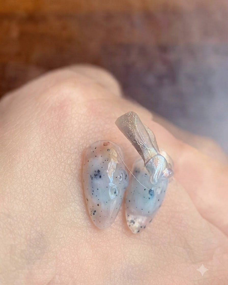 Un primo piano di un pennello per unghie che applica un gel base coat trasparente su ununghia naturale.