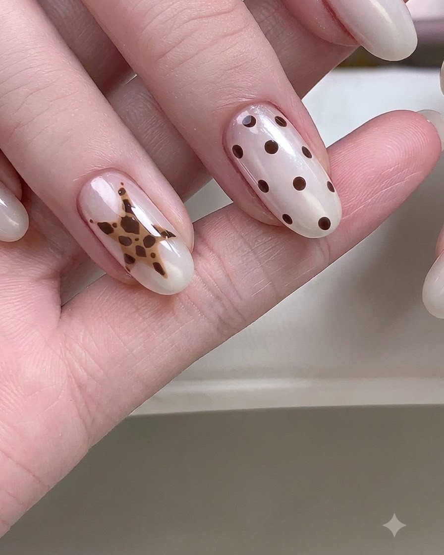 Una mano in primo piano che mostra unghie con dettagliate nail art a stella e pois.