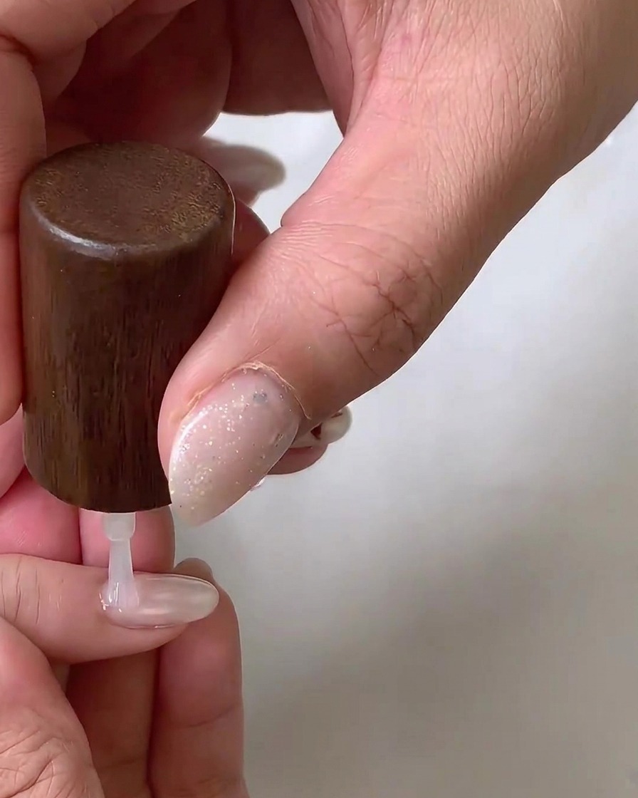 Una fresa elettrica con una punta ceramica a forma di fiamma rifinisce con cura larea delle cuticole di ununghia naturale.