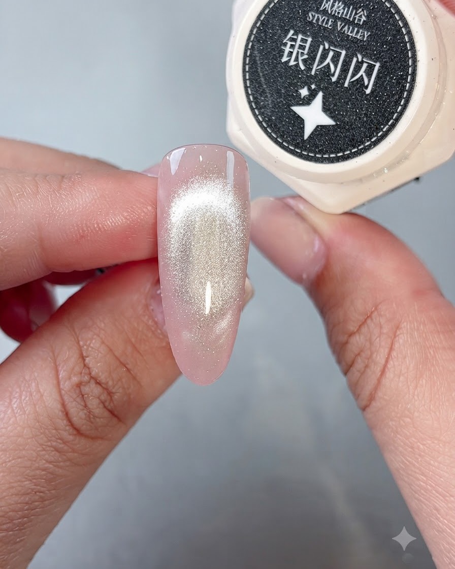 Un pennello che posiziona del gel glitter argento brillante sulla punta di ununghia completata con il cat-eye.