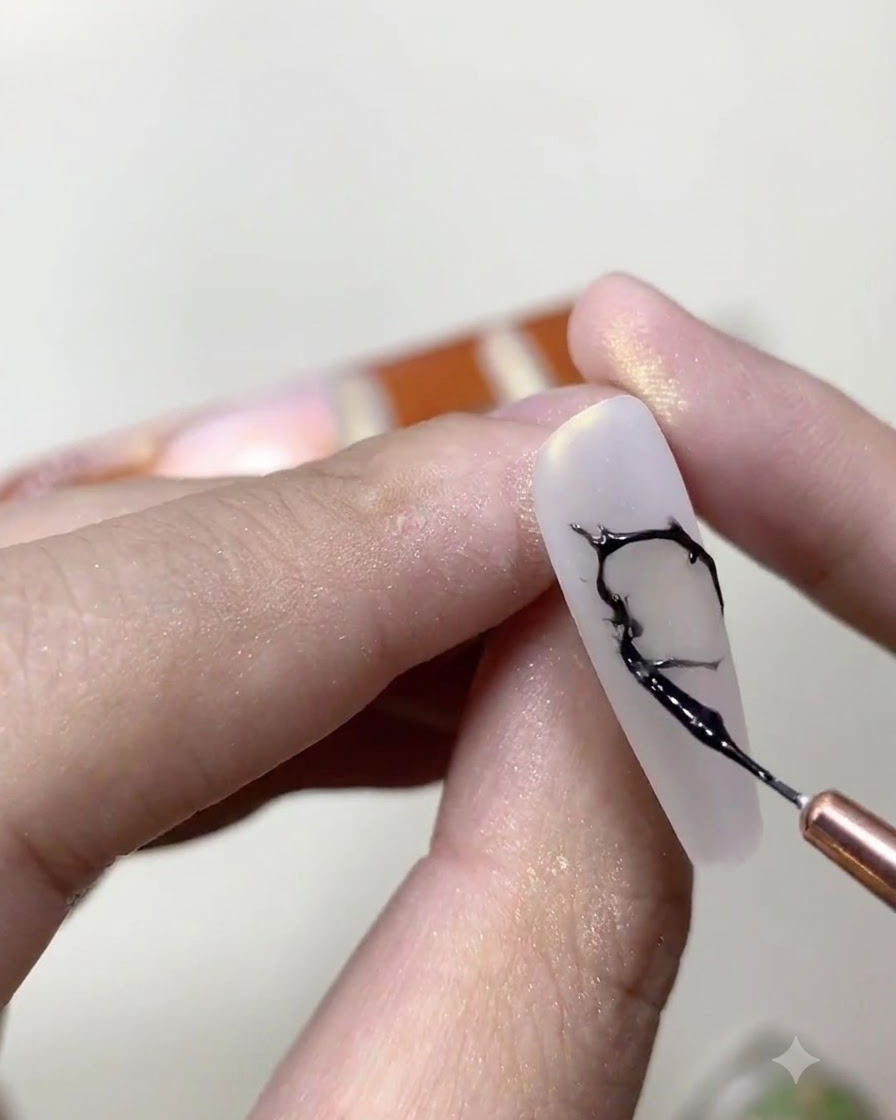 Un pennello sottile da liner che mescola smalto semipermanente nero e colla per strass trasparente su una tavolozza cosmetica.