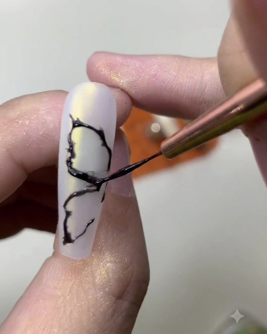 Primo piano di una onicotecnica che aggiunge sottili dettagli interni a un design di ala di farfalla nera dipinta.