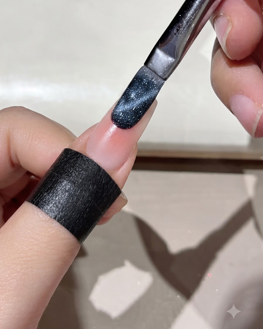 Un pennello che applica il gel cat eye blu scuro sul bordo di ununghia preparata.