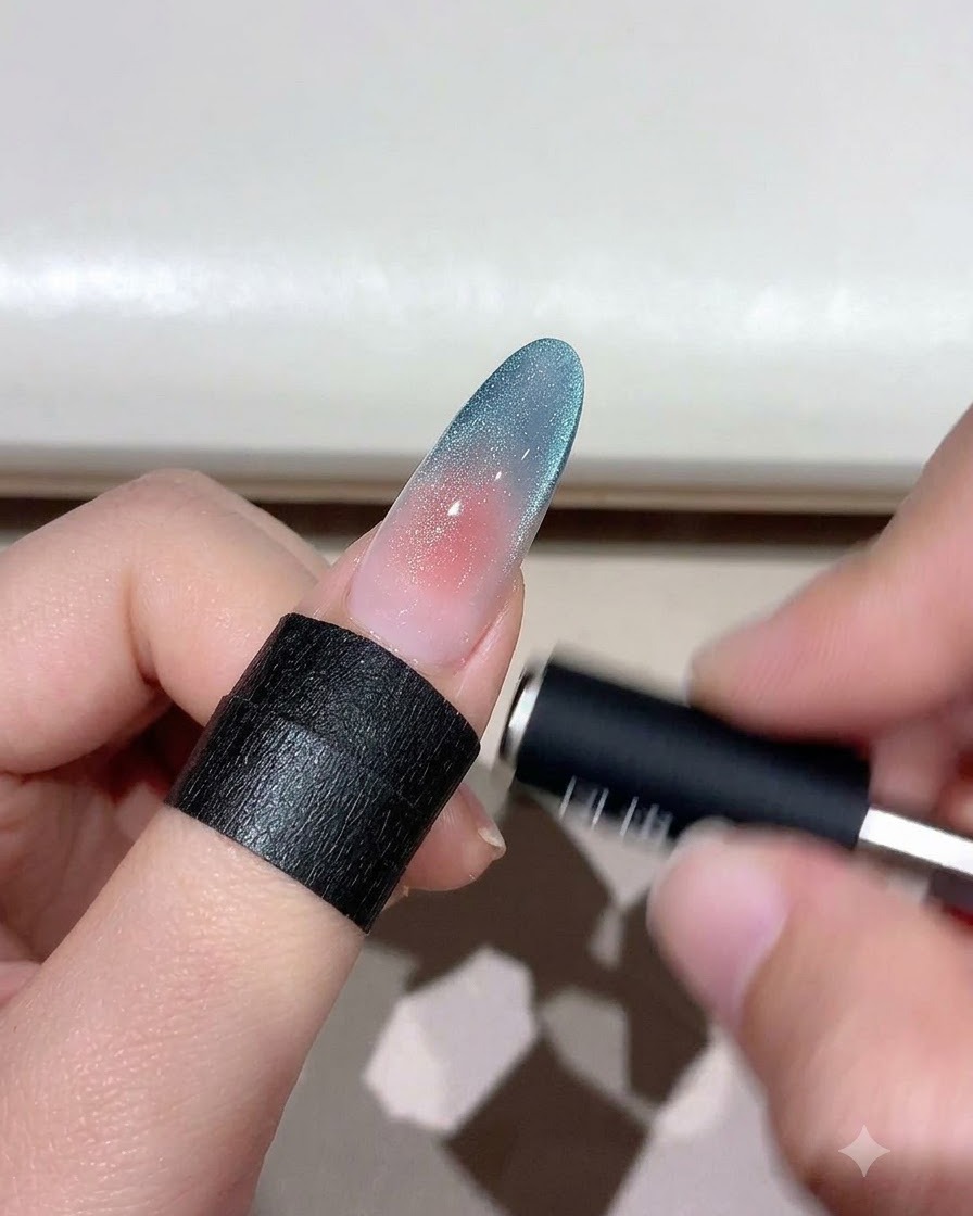 Uno strumento magnetico che si libra su ununghia cat eye sfumata per modellare le particelle di shimmer.