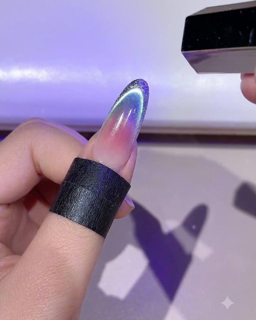 Una mano che tiene una mini lampada LED per polimerizzare il dettaglio del contorno in gel dorato su ununghia.