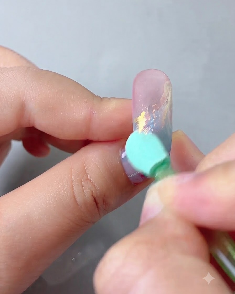 Una spugnetta applicatrice che strofina la polvere aurora magic mirror sulla superficie dellunghia decorata.