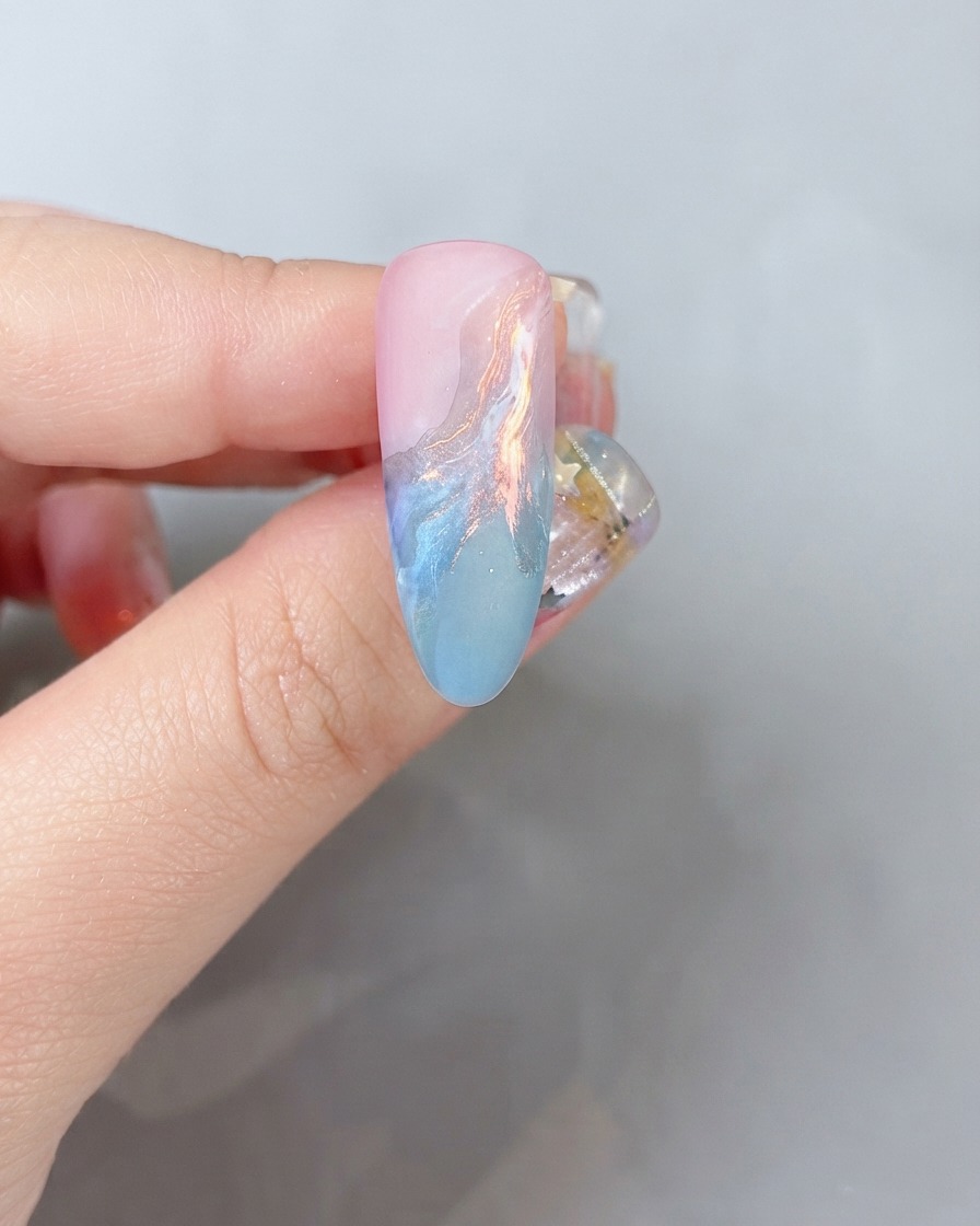 Una vista ravvicinata della superficie di unghia che riceve una leggera spolverata di polvere di glitter colorata.