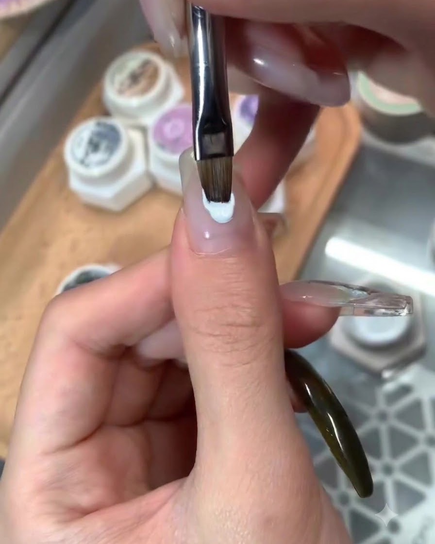 Un pennello che stende un top coat lucido sopra una nail art ultimata a tema blu.