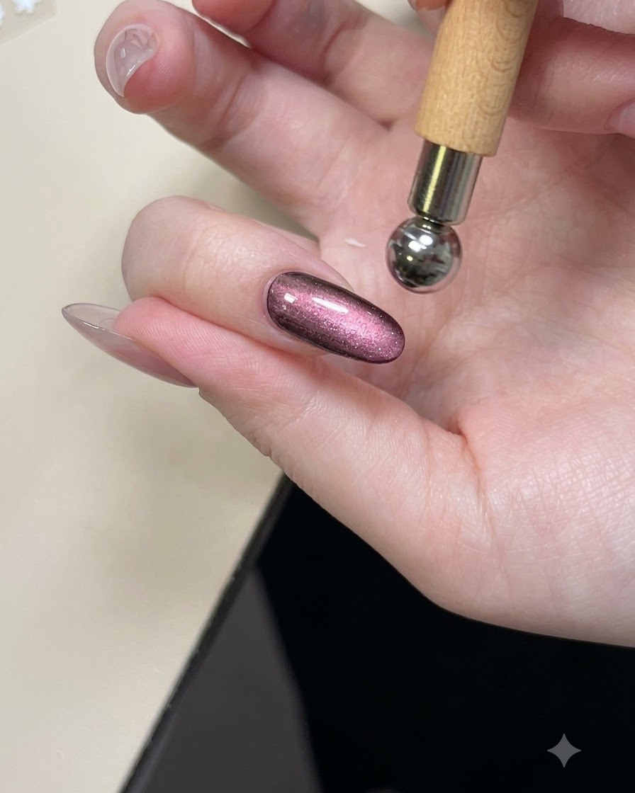 Uno strumento magnetico tenuto sopra ununghia lucida cat eye viola per modellare la brillantezza.