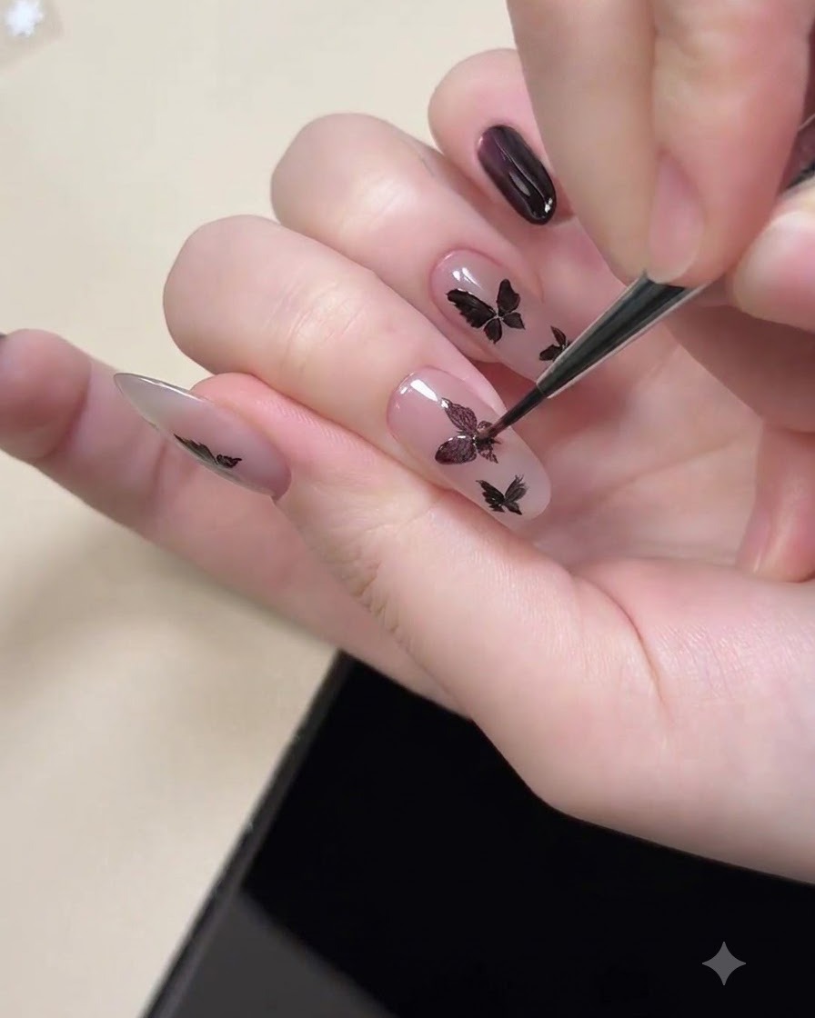 Uno strumento magnetico tenuto vicino a ununghia per magnetizzare la brillantezza cat eye viola allinterno delle forme di farfalla nere dipinte.