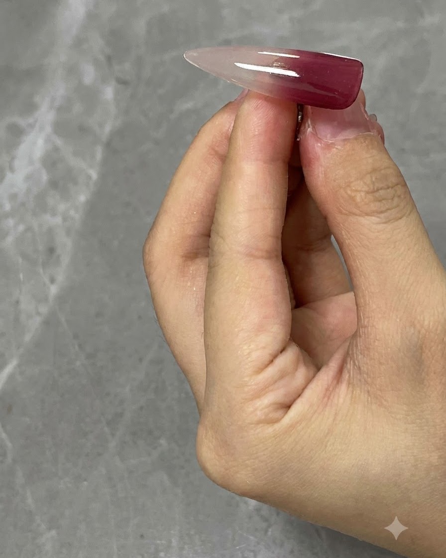 Una tip per unghie trasparente che mostra unapplicazione di rosso vino sulla sezione superiore.