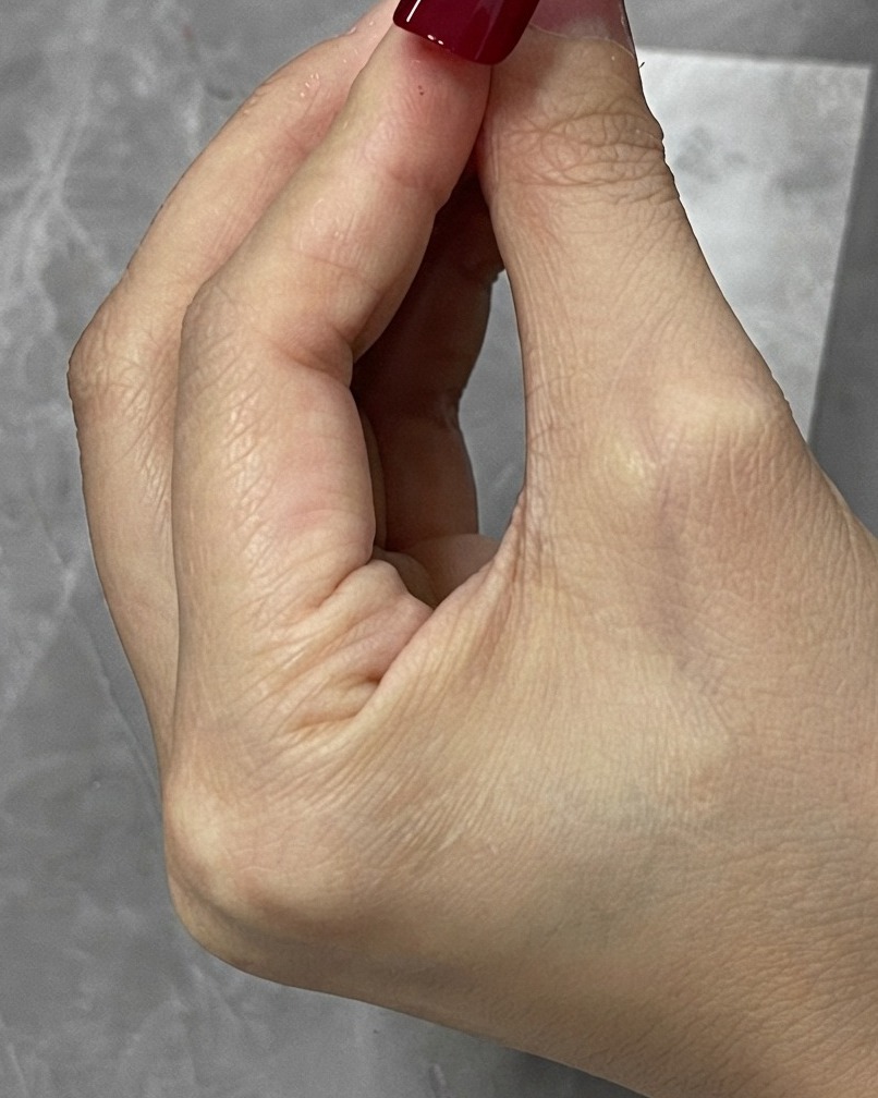 Un pennello di pulizia che rimuove il gel rosso in eccesso attorno ai bordi di una tip per unghie.