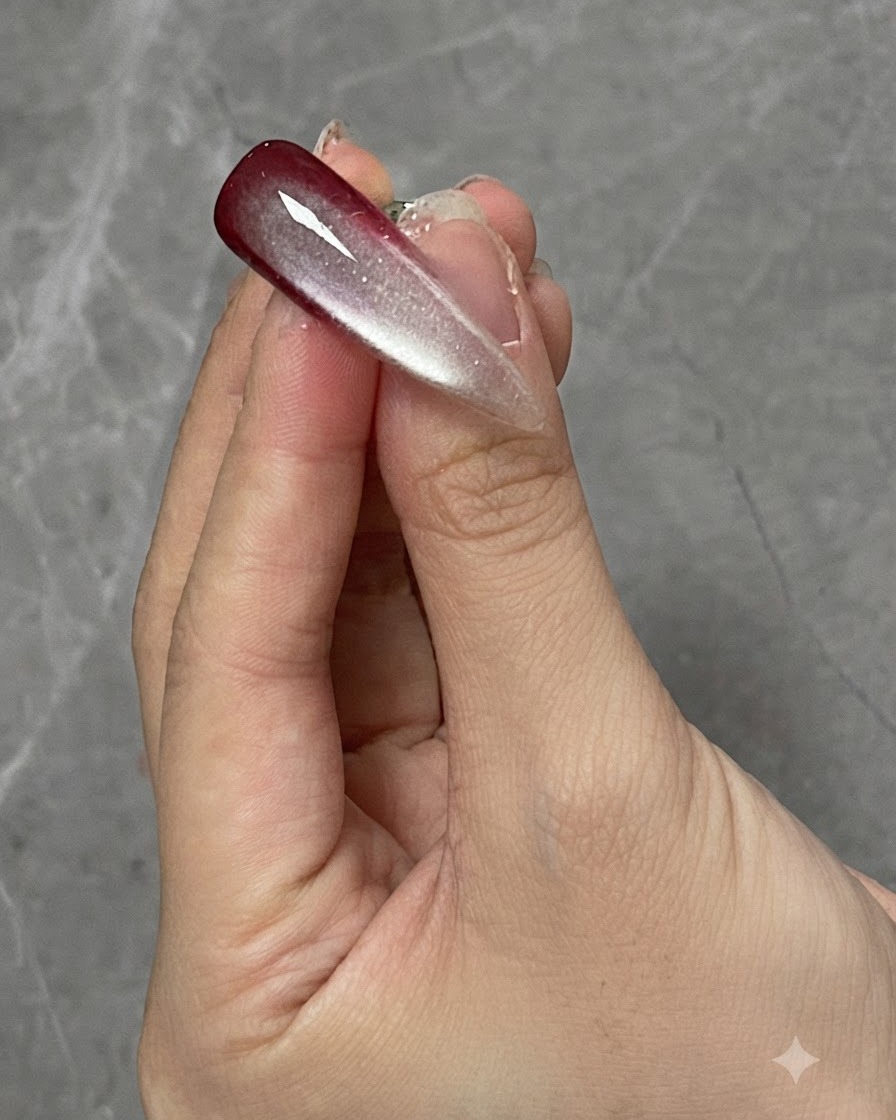 Un dito con un design di unghia sfumato e cat eye polimerizzato posizionato sotto una lampada di polimerizzazione.