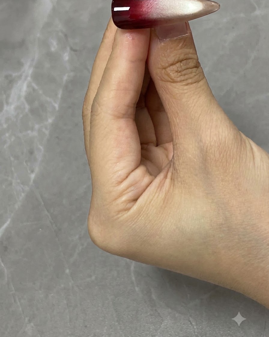 Un pennello per nail art che applica il gel rosso traslucido sulla metà superiore di ununghia decorata.