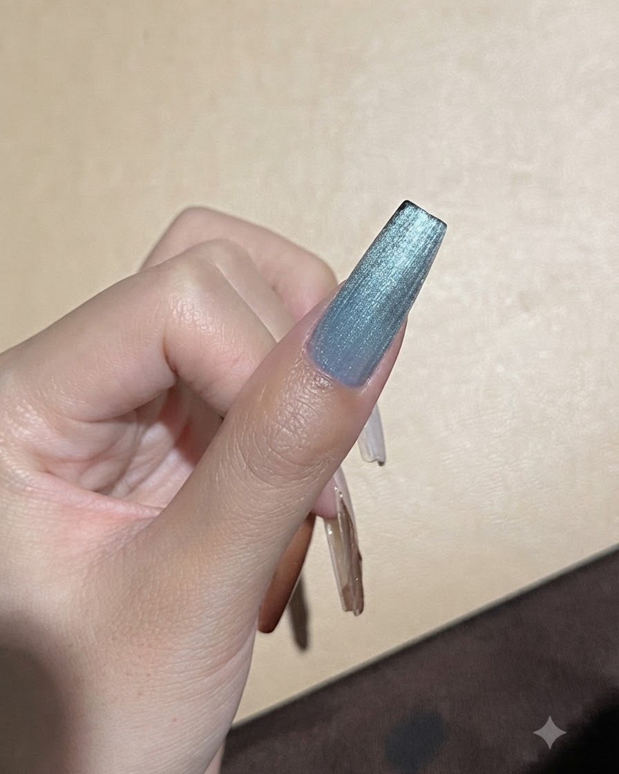 Un forte magnete tenuto vicino a ununghia in gel cat-eye blu per perfezionare la linea di riflessione della luce.