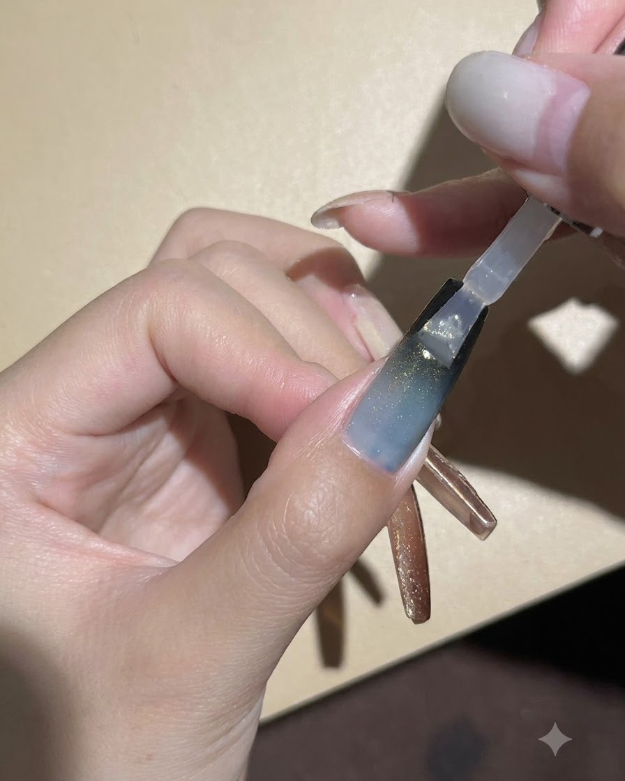 Un pennello per unghie applica un top coat lucido trasparente sopra la sfumatura scura e il gel cat-eye.