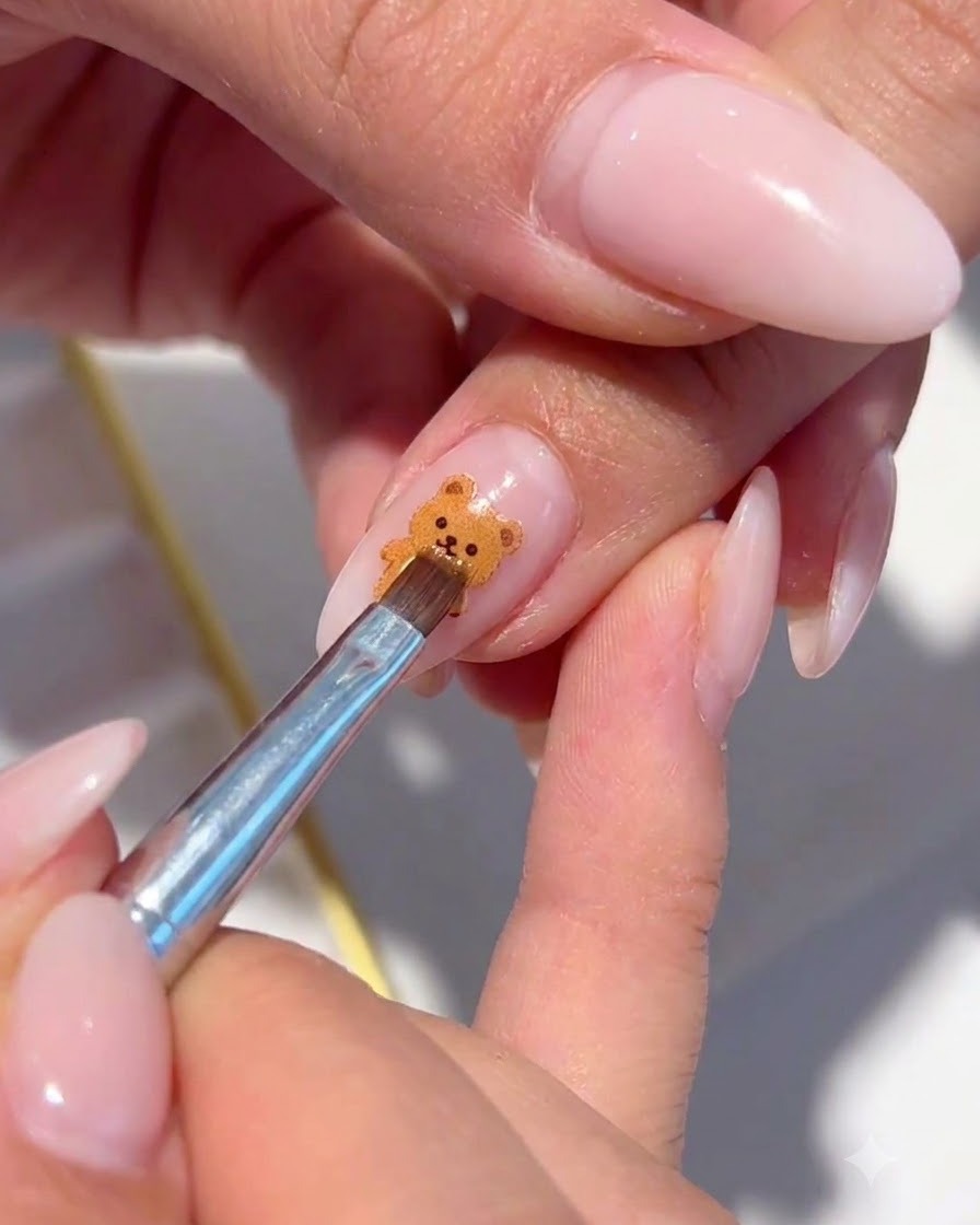 Un pennello fine che posiziona scaglie di glitter iridescenti attorno alla nail art floreale dipinta.