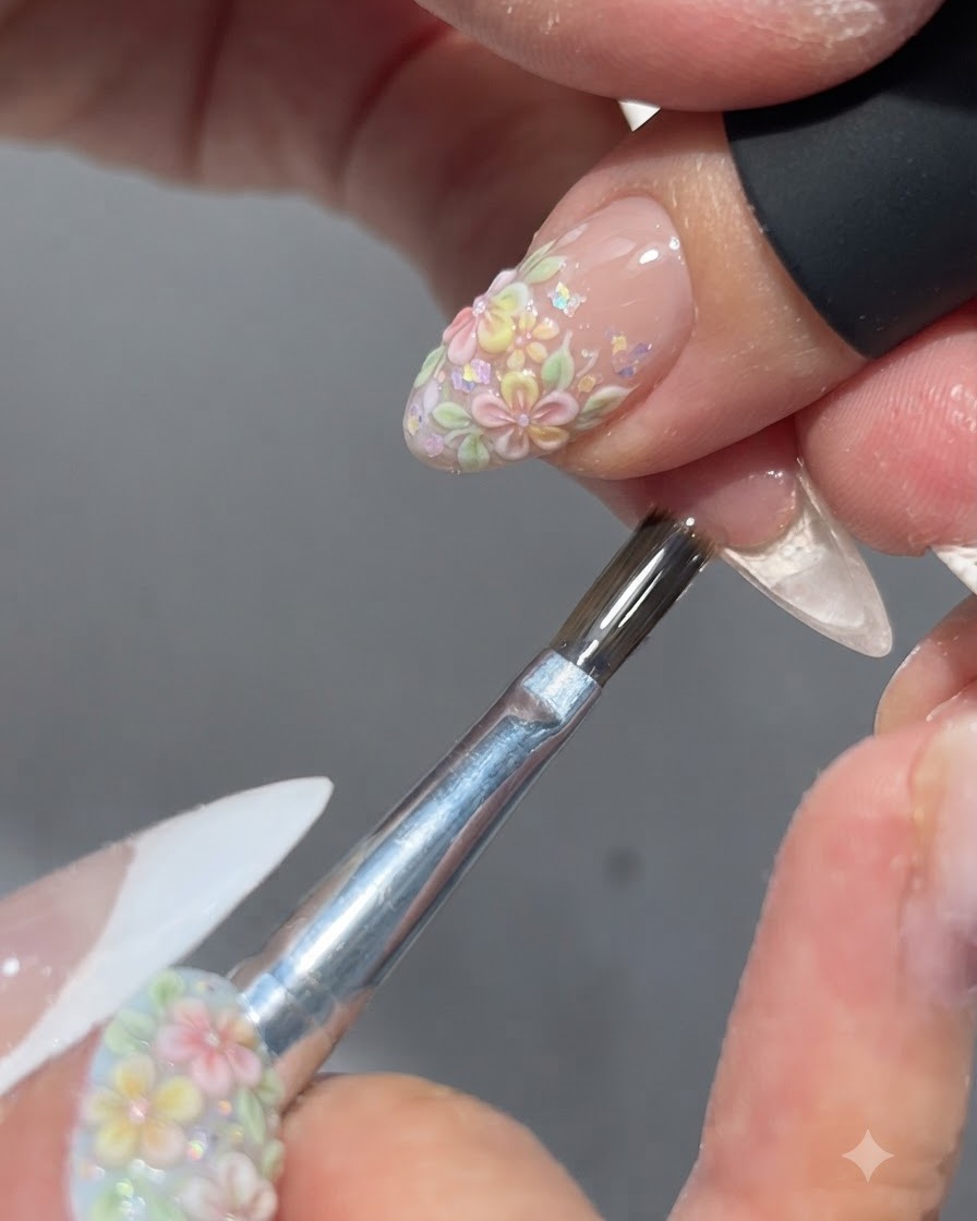 Un pennello che applica un top coat lucido su un design floreale per unghie completato.