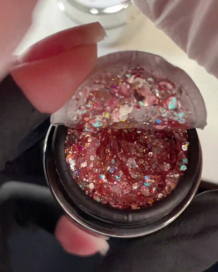 Barattolo aperto di gel denso ricco di sequins glitter rosa, olografiche e duochrome.