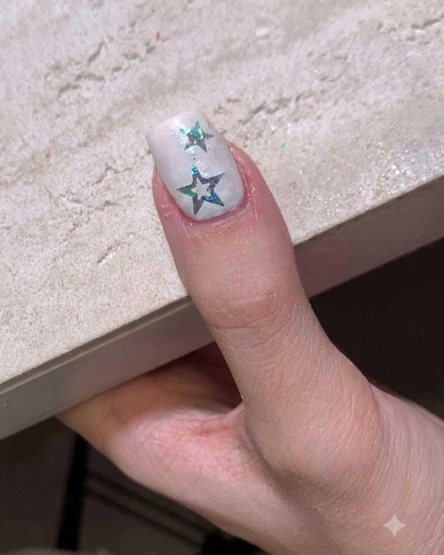 Ununghia con adesivi a stella posizionati sotto una piccola lampada di polimerizzazione LED portatile.