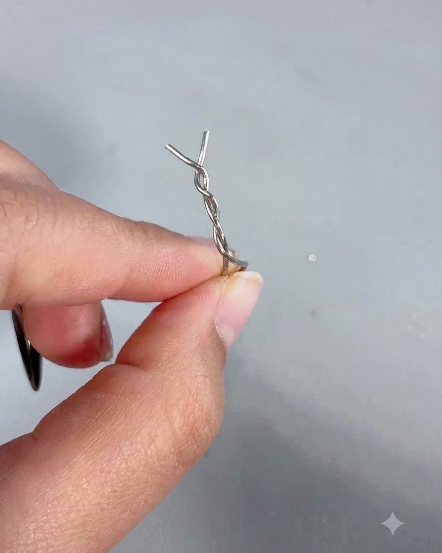 Una mano che regge una bacchetta magnetica con una forcina di metallo attorcigliata fissata sulla punta.