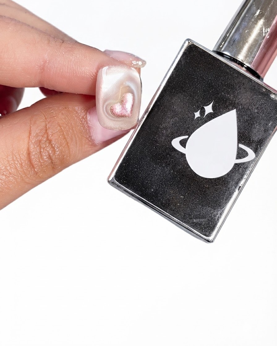 Ununghia preparata accanto a una bottiglietta nera di top coat con un logo bianco raffigurante un pianeta e una goccia.