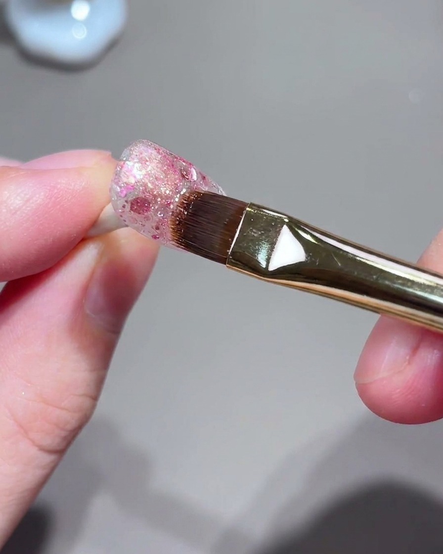 Un pennello e una postazione unghie durante il processo di cattura della luce magnetica cat-eye.