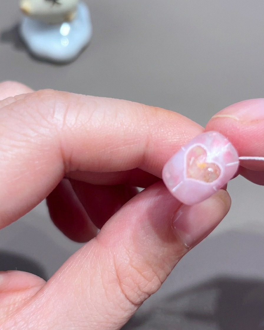 Un primo piano di ununghia che mostra linee radiali bianche sottili disegnate verso lesterno da una forma a cuore centrale.