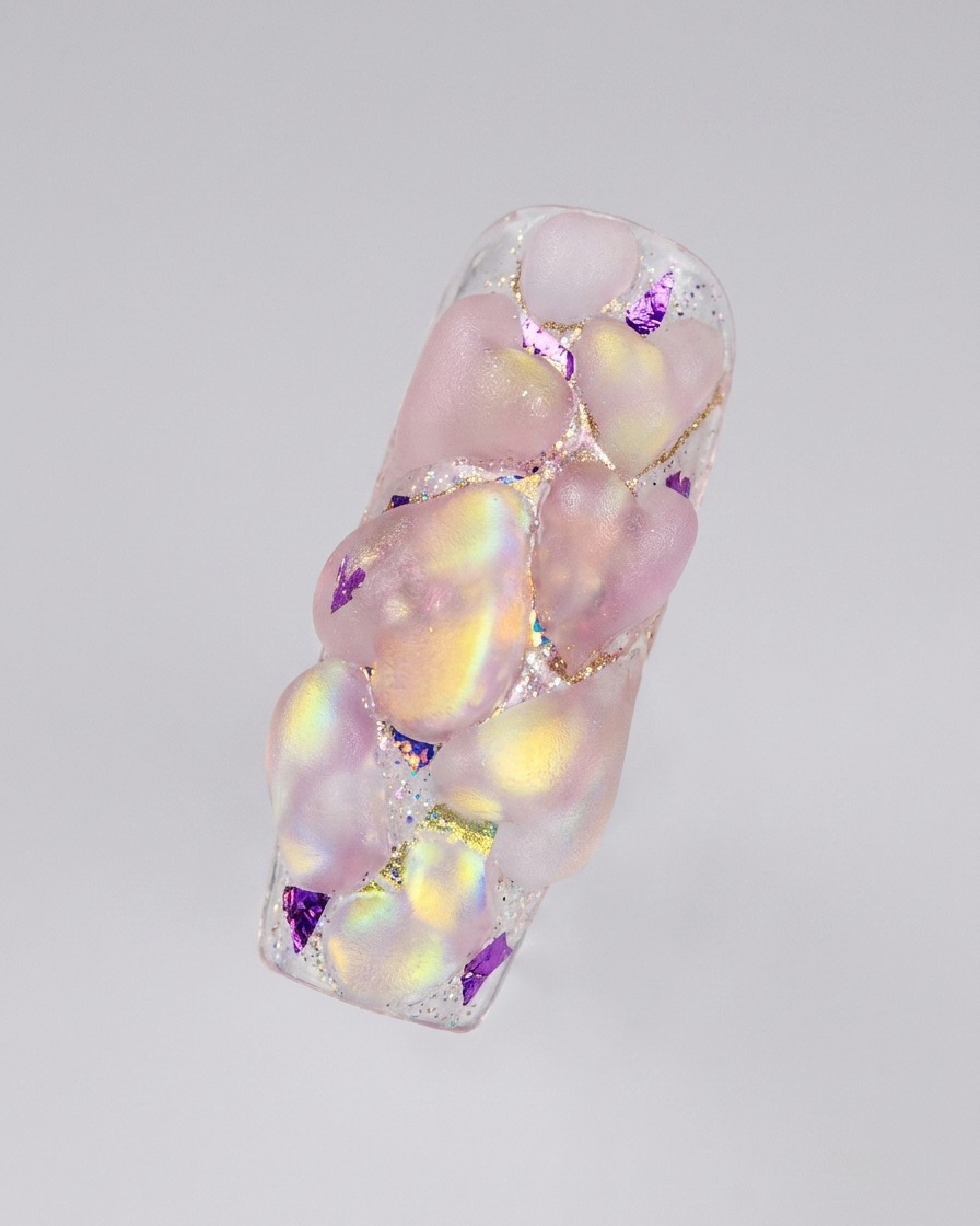 Una disposizione completata di molteplici cuori acrilici 3D iridescenti che coprono una superficie ungueale allungata.