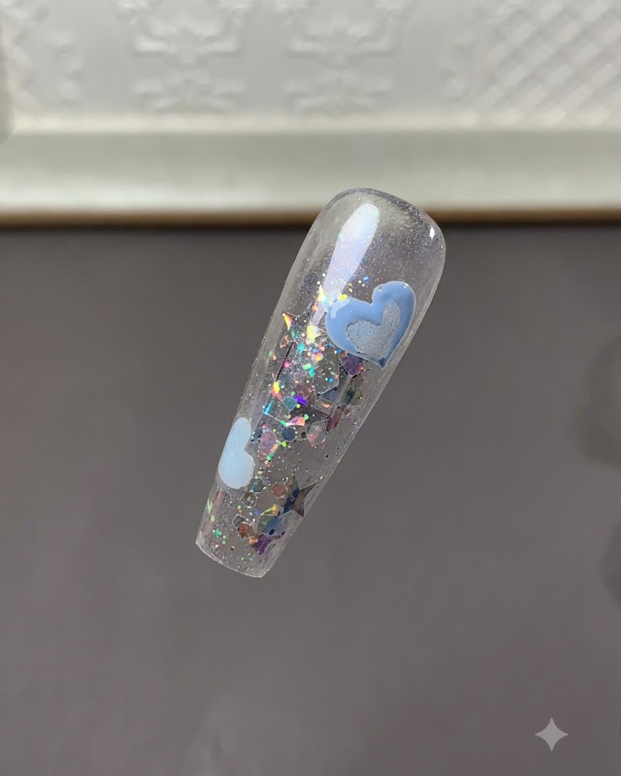 Una vista ravvicinata della tip dellunghia che mostra i design di cuori azzurri polimerizzati in mezzo a scaglie di glitter.
