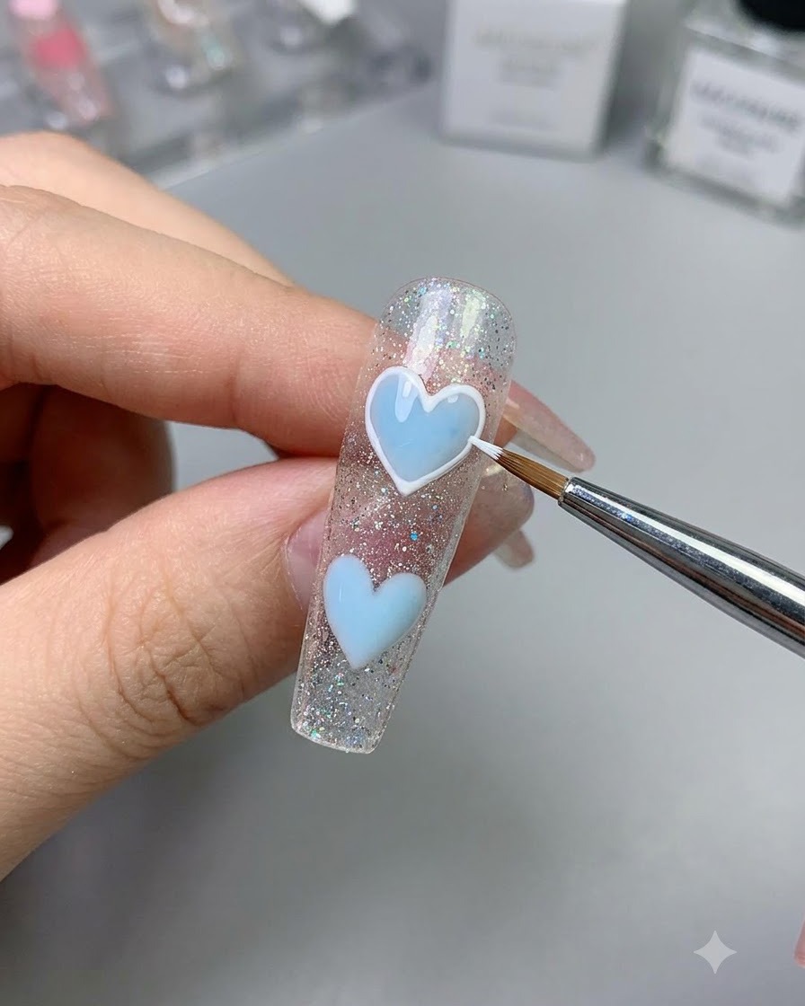 Un pennello fine che utilizza gel da disegno bianco per delineare i bordi di un cuore azzurro.