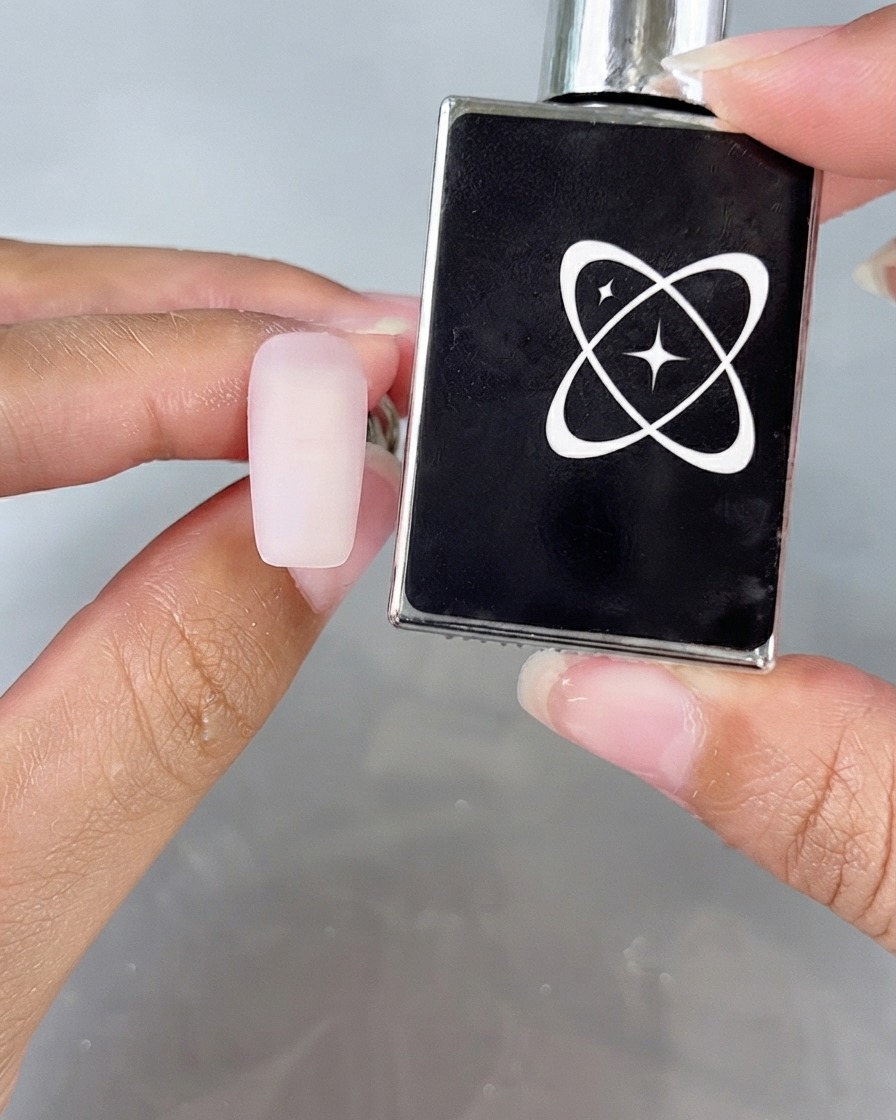 Una superficie dellunghia dallaspetto opaco accanto a un flacone di top coat anti-polvere.