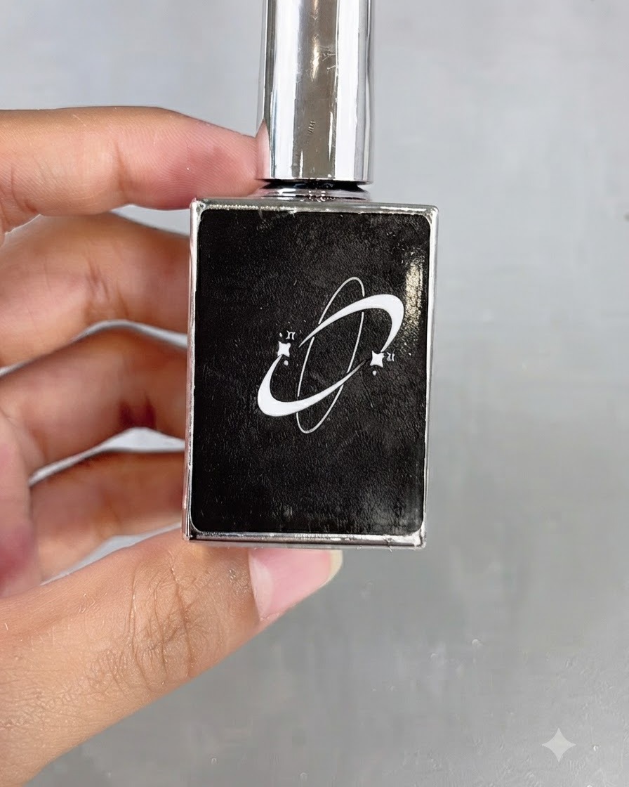 Un flacone di cosmetici nero con un logo grafico a forma di pianeta tenuto in mano.