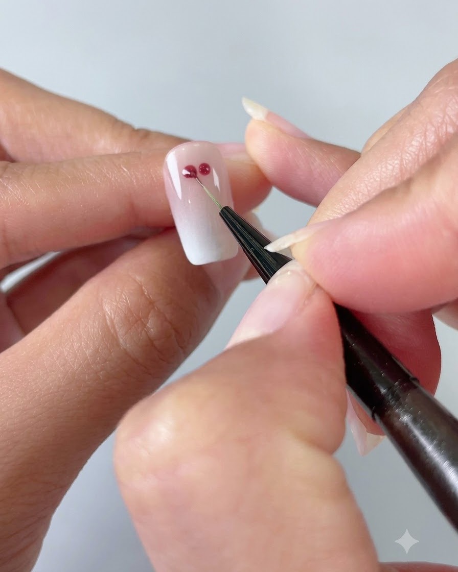 Un sottile pennello da nail art che collega due punti in gel rosso in una forma a cuore su ununghia sfumata cat-eye.