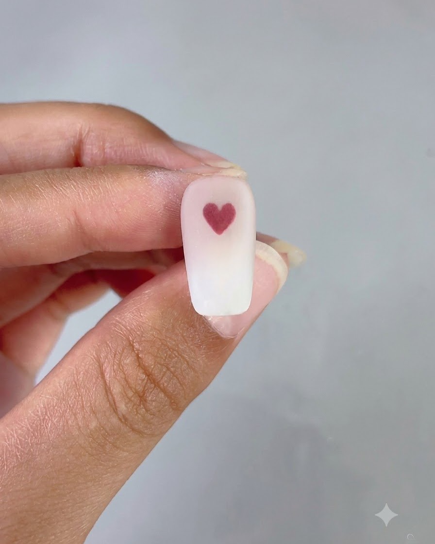 Ununghia finita che mostra uno sfondo sfumato pulito rosa e bianco con un cuore rosso pulito al centro.